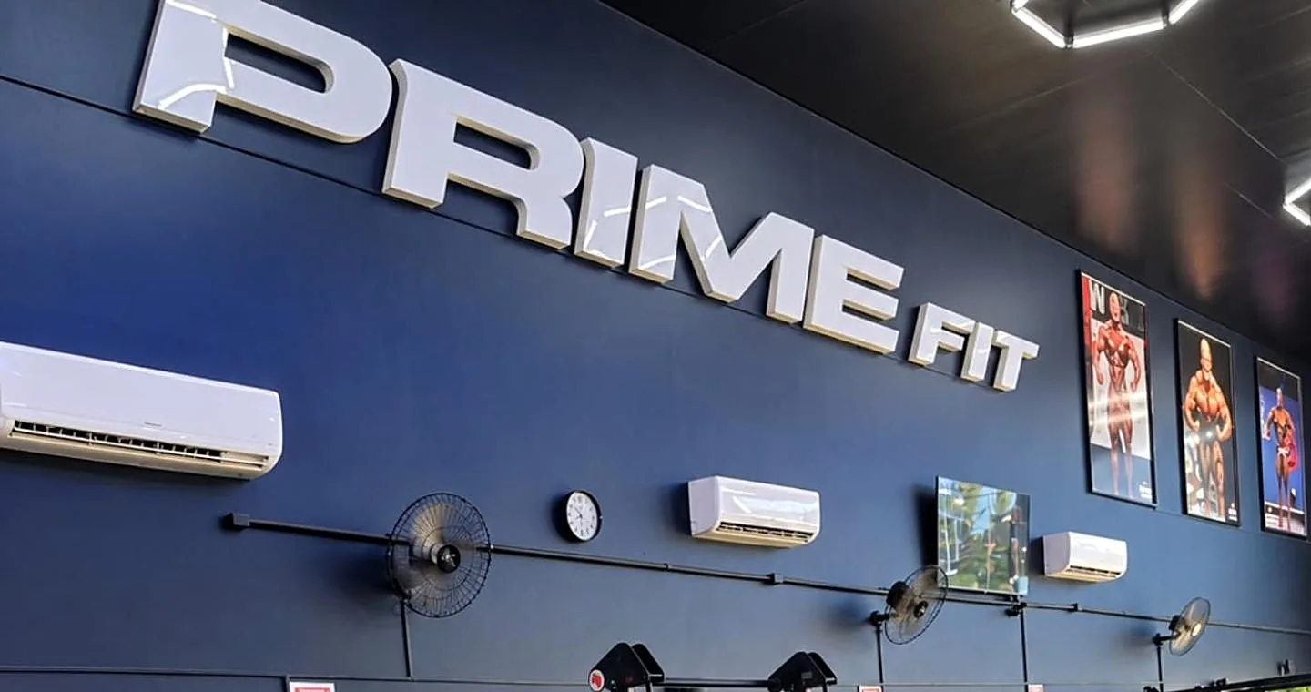 Parede azul com o letreiro Prime Fit e luzes hexagonais